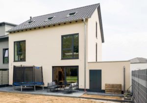 Eine Außenansicht eines modernen Neubaus eines Einfamilienhauses in Form einer Doppelhaushälfte mit drei Stockwerken und Garten in Ketsch. Entworfen durch die erfahrenen Architekten des Architekturbüros Goldstein Baukonzepte.